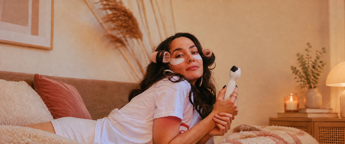 Woman holding the Mesanel cat-head wand vibrator in a warm bedroom